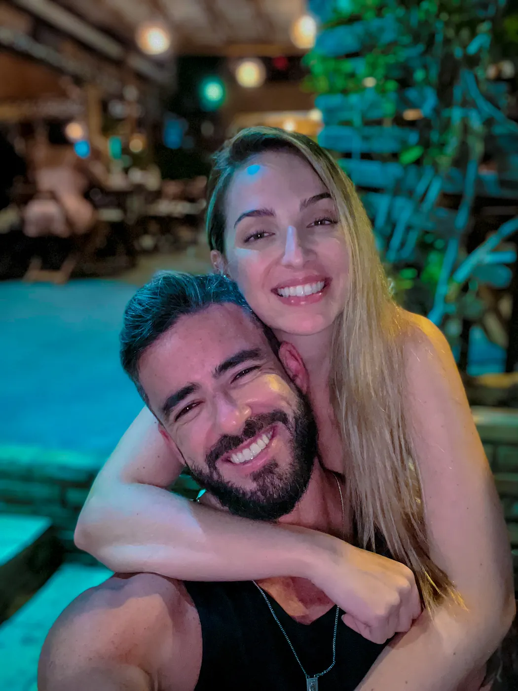 O casal abraçado à beira de uma piscina à noite